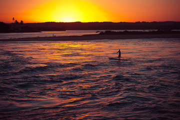 Silhouette of man doing boating on the river during sunset.
