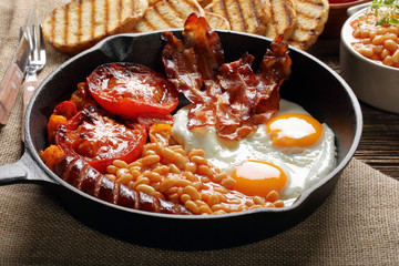 English Breakfast in the pan including sausages, grilled tomatoes, egg, bacon, baked beans and toast bread