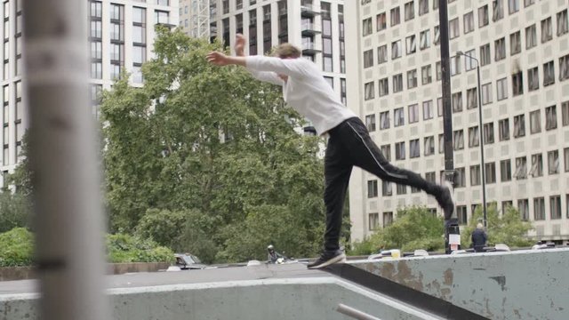Young parkour male running and flipping in the city, in slow motion