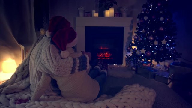 Couple sitting in Santa Hat near fireplace in living room