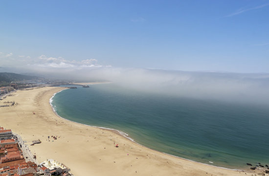 Scenic View Of Nazare Beach. Coastline Of Atlantic Ocean. Portuguese Seaside Town On Silver Coast. The Clouds Above The Water Are Like Tsunami Waves. Nazare, Portugal.