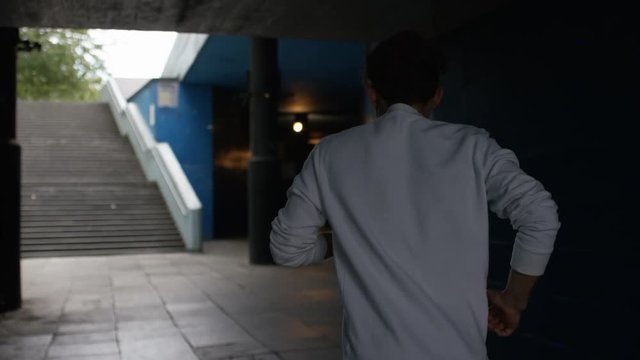 Camera follows a man jogging in urban city environment, in slow motion