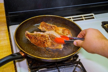 Two fat juicy pork steak fried in the olive oil in a frying pan