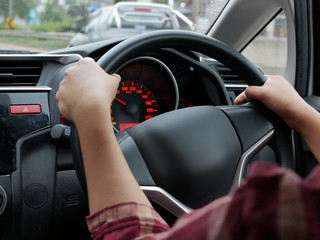 Selective focus of woman hand on steering wheel driving a car with both hand