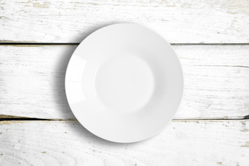Top view of empty white food plate on a wooden background.
