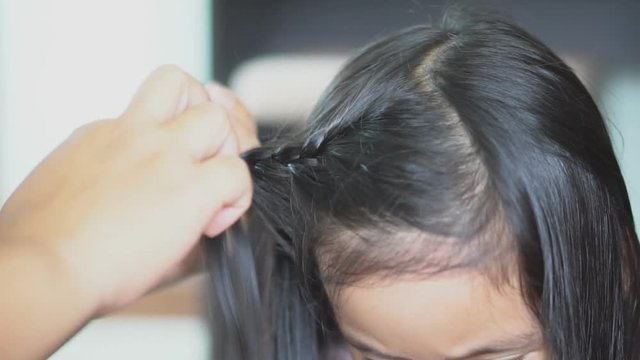 asian child cute or kid girl with hand of mother braided the daughter in hair salon shop for beauty and fashion with care and love after shower and before go to school on slow