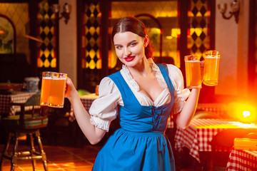 Young beautiful girl holds four glasses of beer in hands at celebration oktoberfest.