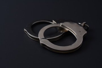 Metal handcuffs on black background