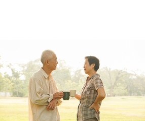 Asian elderly couple drink tea coffee in moring park sun light