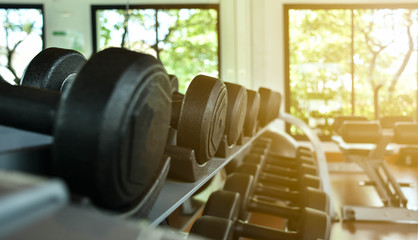 Dumbbells lie in a row on the inventory rack in the gym or fitness center  background. health concept.