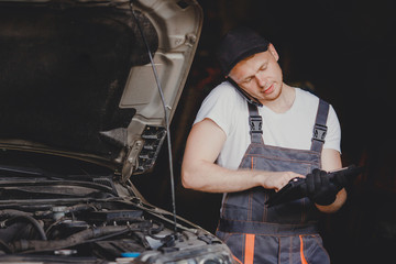 Professional car mechanic Calls on phone to client in auto repair service.