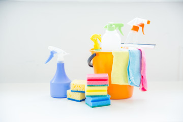 Bucket with cleaning supplies and tools on table