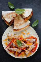 Tortilla bread with roasted chicken, vegetables and cheddar cheese for making quesadilla, high angle view