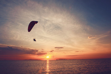 Beautiful Silhouette of Paramotor flying in the sky of sunset on the beach and sea at Koh-Samui in Surat Thani Province, Thailand