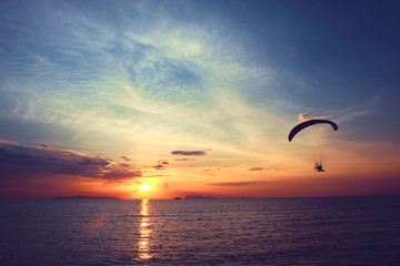 Beautiful Silhouette of Paramotor flying in the sky of sunset on the beach and sea at Koh-Samui in Surat Thani Province, Thailand