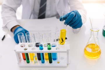 Medical scientist, or medical researcher looking at a test tube containing a clear solution in a laboratory.