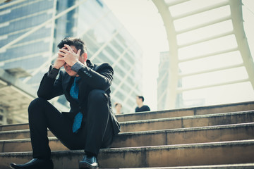 Businessman disappointment of being denied a job, he sat on the steps with hands on head.