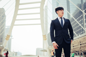 Young businessman confident in suit, adjusting arms and looking out into modern city.