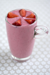 Fresh milk and strawberries drink in the glass on floral pattern tablecloth, tasty and healthy fruit milkshake