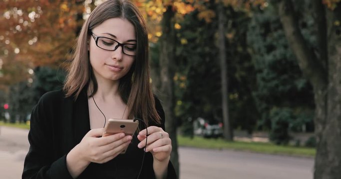 Woman listening to music or audiobook while walk in autumn city