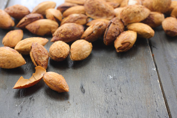 Close up of honey roasted almonds nuts with sesame on a black wooden table