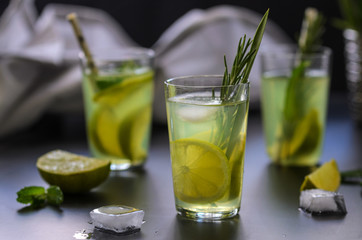 Mojito cocktail, lime, mint  and ice in glass decorated with herbs on dark background.