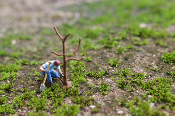 Planting a tree , Miniature figure Young man planting the tree with shovel while working in the garden