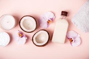 Fototapeta na wymiar Coconut oil and halves of fresh coconut on a pink background. Hair care spa concept