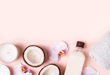 Coconut oil and halves of fresh coconut on a pink background. Hair care spa concept