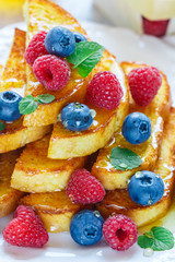 Traditional Breakfast - French toast with honey and fresh berries - raspberries and blueberries in a white plate on the table