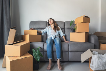 Young tried woman moving in new home, sitting and relaxing on sofa