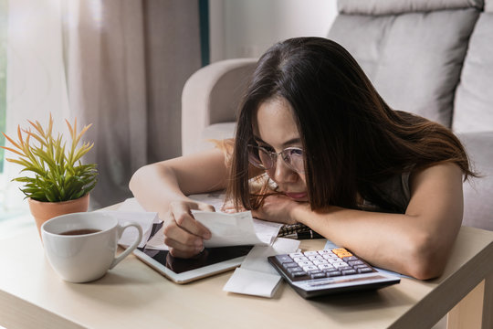 Stressed young woman checking bills, taxes, bank account balance and calculating expenses in the living room at home