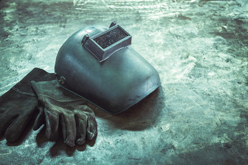 Inverted welding machine welding equipment on a wooden desk with welding mask, leather gloves,...