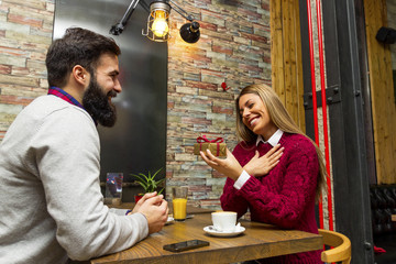 Man giving a present to his girlfriend in cafe and she is surprise