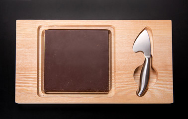 Square slab of milk chocolate on a wooden board