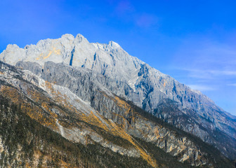 The steep snow-capped mountain top, the fir forest above is sparse in the Jade Dragon Snow Mountain in Lijiang City, Yunnan Province, China.