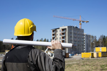Construction worker in dirty overalls and a yellow helmet in Finland. In his hand he has drawings....