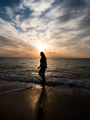 Young woman towards the beautiful sunset on the sea beach. Enjoying the moment