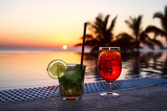Two colorful drink at the pool-side in Spain. A beautiful sunset in the background out of focus. Image includes a effect.