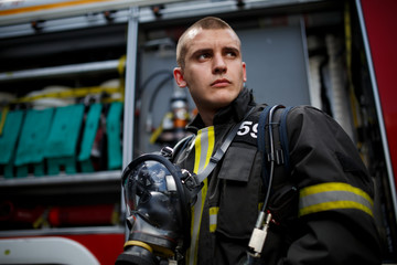 Photo of young fireman near fire engine
