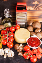 Raw uncooked spaghetti, pasta and macaroni next to fresh vegetables on rustic background