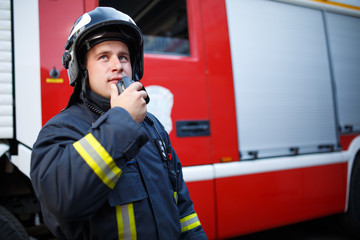 Photo of fireman talking on walkie-talkie with fire engine