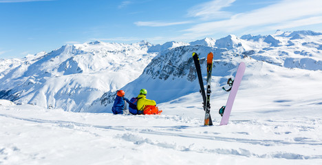 snowboarder and skiier sitting on snow and see at mountains