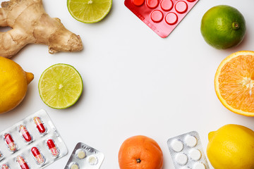 Photo of blisters with tablets, ginger, lemon, lime, orange on empty white space.