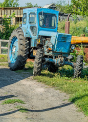 Village. Rural. Technique. Old tractor in the yard of one of the houses.