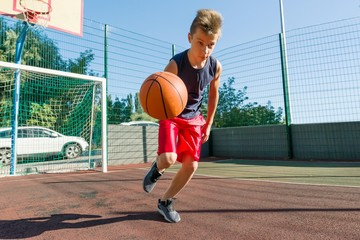 Outdoor portrait street basketball player playing with the ball on sunny day
