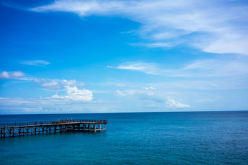 Fototapeta na wymiar wood pier and calm ocean water with blue sky and clouds