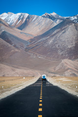 A truck driving ahead on a straight road toward mountains