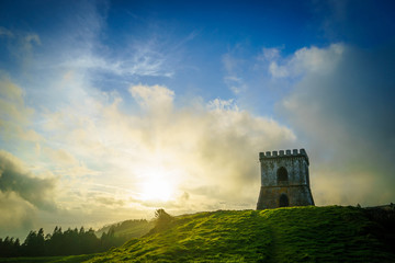 Naklejka premium a fortress on a green hill during a beautiful sunset