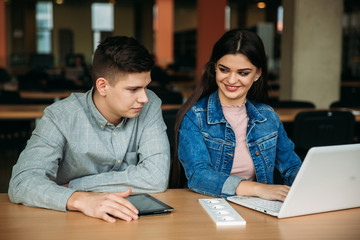 Boy and girl study in library use laptop and help each other